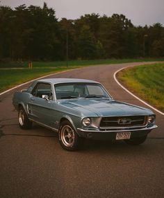 an old mustang is parked on the side of the road