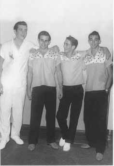 black and white photograph of four men in scrubs posing for the camera with their arms around each other