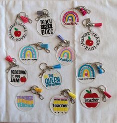 a bunch of key chains that are on top of a white cloth with the words teachers and rainbows