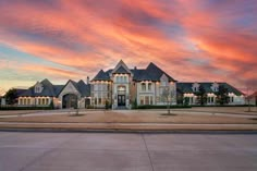 a large house with lots of windows and lights on it's front yard at sunset