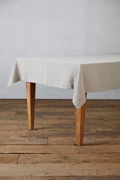 a white table cloth on top of a wooden bench in a room with hard wood flooring