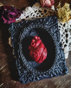 a red heart in a black frame surrounded by crocheted doily