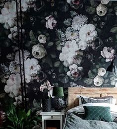 a bed sitting in a bedroom next to a wall with flowers on it and a lamp