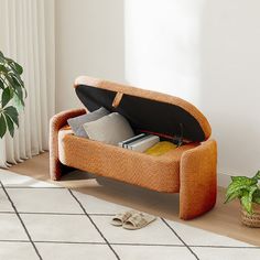 an open suitcase sitting on top of a floor next to a potted plant and slippers