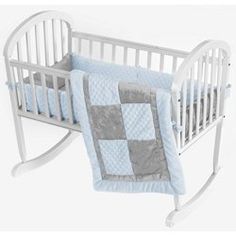 a baby crib with a pink and grey quilt on it's bedding