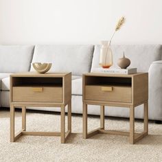 two side tables sitting on top of a carpeted floor next to a white couch