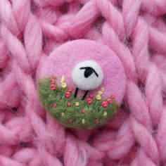 a close up of a pink knitted object with a sheep in the center surrounded by flowers