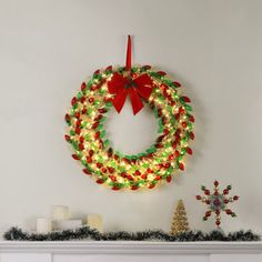 a christmas wreath is hanging on the wall next to a fireplace with candles and decorations