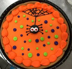 a cake decorated with orange icing and green polka dots, spider on it's face