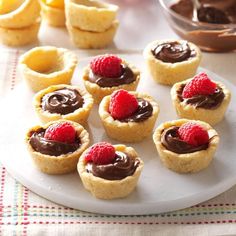 small desserts with chocolate and raspberries on a plate next to lemon wedges