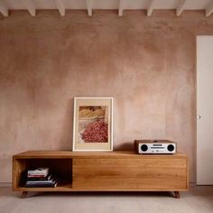 a wooden entertainment center with a radio on top of it next to a painting and bookshelf