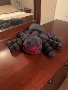 a stuffed spider sitting on top of a wooden dresser