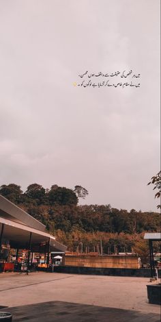 an empty parking lot with trees in the background and writing on the sky above it