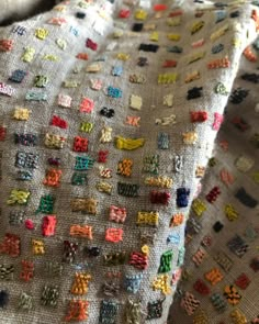 a close up of a piece of cloth covered in small colorful squares and crosses on it