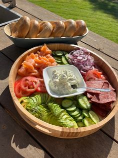 a wooden bowl filled with different types of food on top of a table next to bread