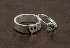 "Set of Handmade Skull rings in Sterling Silver.  These rings have a simple but original and elegant design.  The Little ring skull for her  is shiny, flat and smooth and it has 2 beautiful  black zirconias in the eyes.  The ring for him stands out for the contrast between the small skull and the width of the band that has a very industrial look. Both together are the perfect match. If you are looking for a different engagement rings this set will be the best rings you'll find! In order to make Sterling Silver Skull Ring For Wedding, Rings Alt, Different Engagement Rings, Sugar Skull Ring, Gothic Wedding Rings, Gothic Engagement Ring, Skull Engagement Ring, Handmade Skulls, Skull Rings