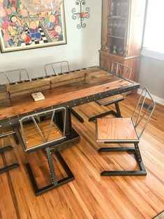 a dining room table with chairs and a bench on the floor in front of a painting