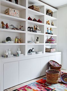 a living room filled with lots of white bookshelves covered in figurines