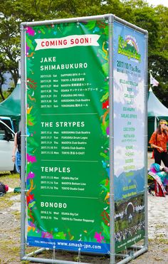 a sign for the upcoming festival is shown in front of people sitting and standing around