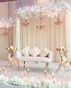 a white couch sitting under a chandelier filled with flowers and candles on top of a table