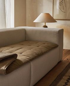 a white couch sitting in front of a lamp on top of a hard wood floor