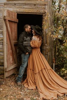 a man and woman are standing in the doorway of an old barn