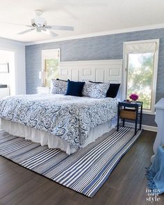 a bedroom with blue and white decor on the walls, wood flooring and a large bed