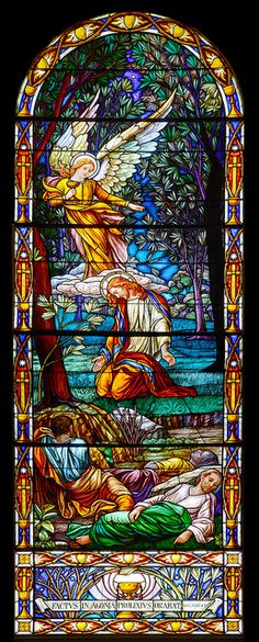 a stained glass window with an angel sitting on the ground