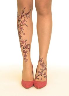 a woman's legs with tattoos on them and flowers painted on the leggings