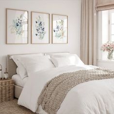 a bed with white linens and pillows in a bedroom next to a large window