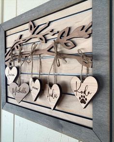 wooden hearts with names hanging from them on a wall next to a dog's paw