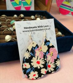 the earrings are on display for sale at the store's booth table, with other items in the background