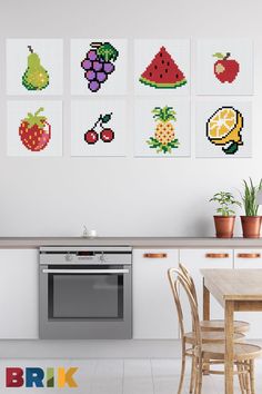 four cross stitch fruits and vegetables are hanging on the wall above a kitchen table with chairs