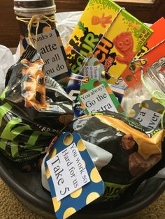 a bowl filled with lots of different types of food and candy bags on top of a table