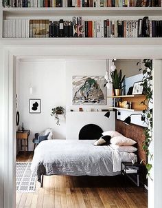 a bed sitting in a bedroom next to a tall book shelf filled with lots of books