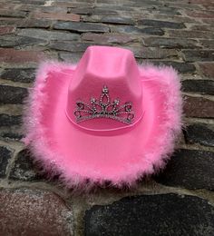 a pink cowboy hat with a tiara on it sitting on a cobblestone road