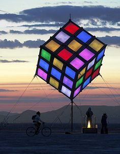 a giant rubik cube is lit up at dusk