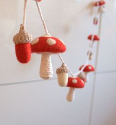 mushrooms are hanging from the ceiling with red and white knitted decorations attached to them