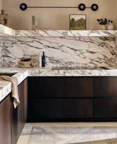 a kitchen with marble counter tops and dark wood cabinets, along with two lights on the wall