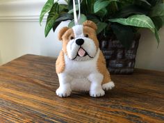 a brown and white dog ornament sitting on top of a wooden table next to a potted plant