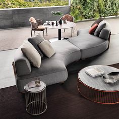 a living room filled with lots of furniture next to a large glass wall covered in greenery