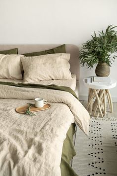 a bed with two pillows and a cup on the end table in front of it