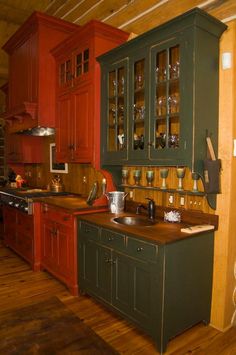 a kitchen with red cabinets and green cupboards on the wall, wood flooring