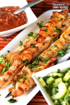 grilled chicken skewers with cucumbers and sauces on the side