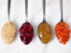 four spoons with different types of jelly on them are lined up in a row