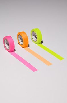 three rolls of neon colored tape sitting next to each other on top of a white surface