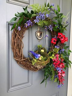 a wreath is hanging on the front door with flowers and eggs in it's nest