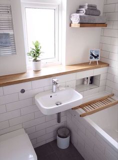 a bathroom with a toilet, sink and bathtub next to a window in it