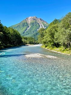 the water is crystal blue and clear with mountains in the background