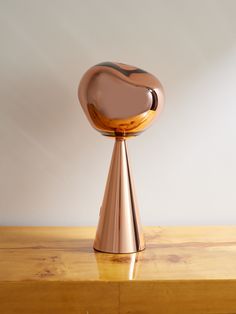 a gold vase sitting on top of a wooden table